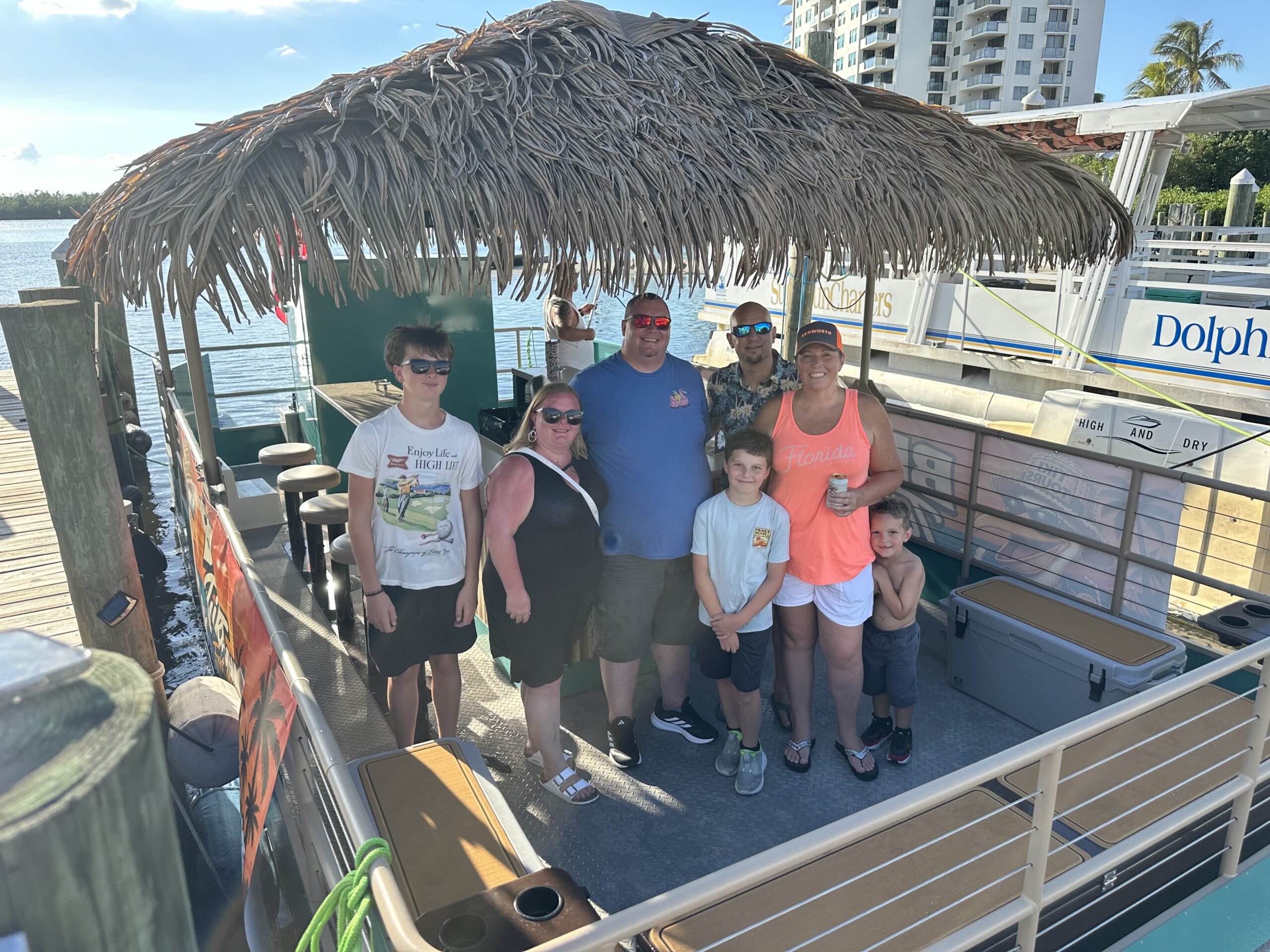 Family and friends posing aboard a Big Tiki Tours boat under the thatched canopy