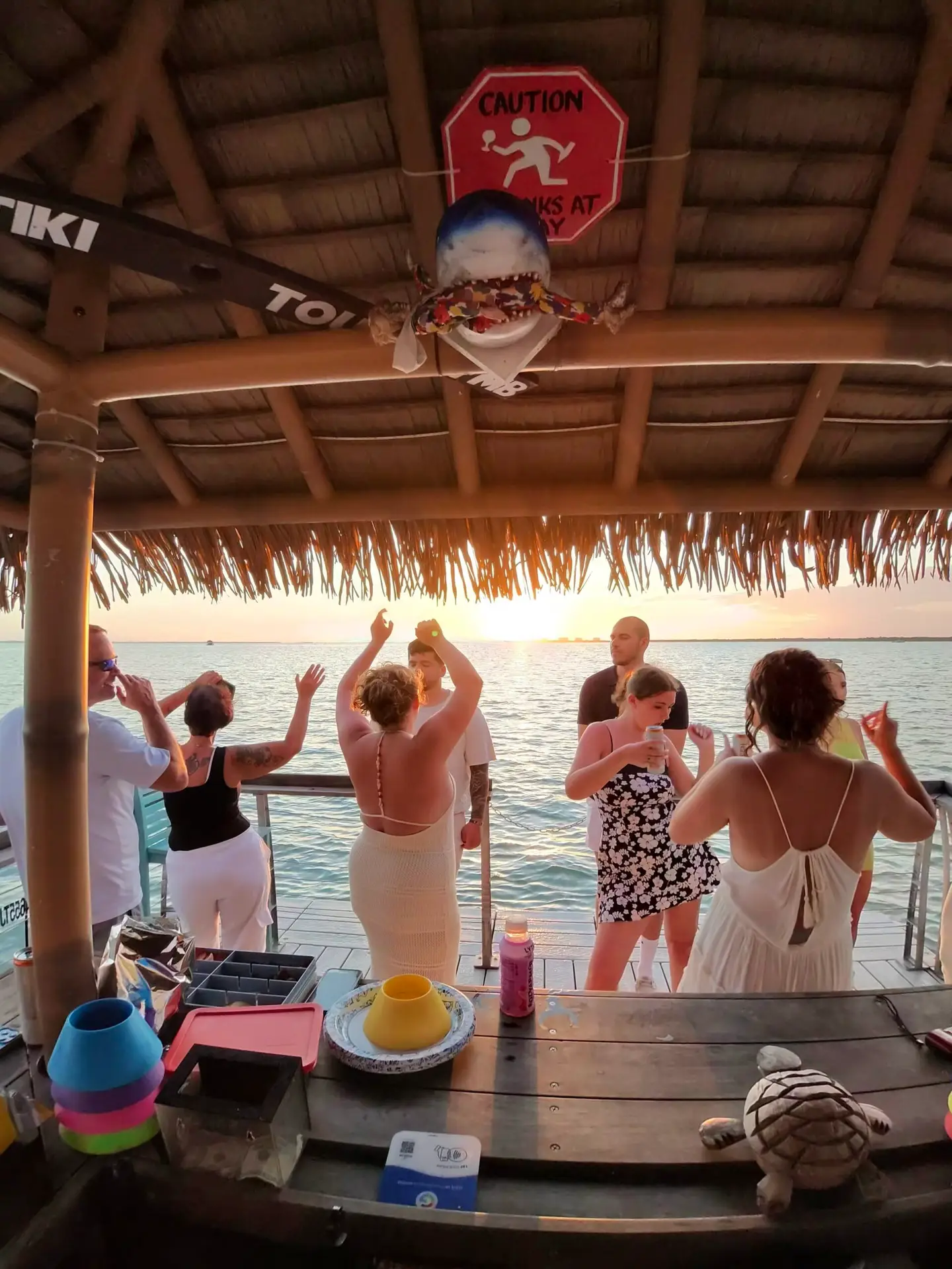 Guests dancing aboard a tiki boat at sunset in Fort Myers Beach